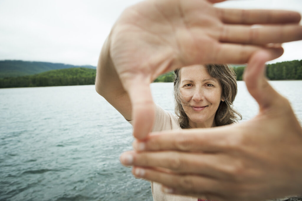 A woman by a lake using her hands to frame her face after having one of our facials near Port Charlotte, FL