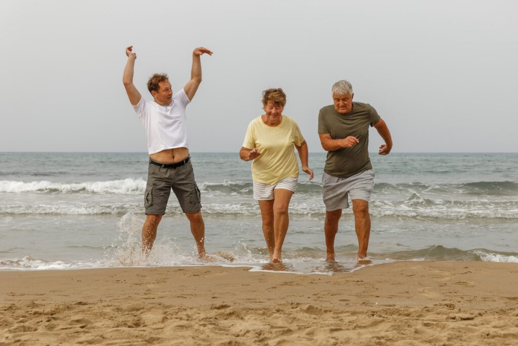 Elderly parents with adult sun having fun on the beach after having body contouring in Wellen Park