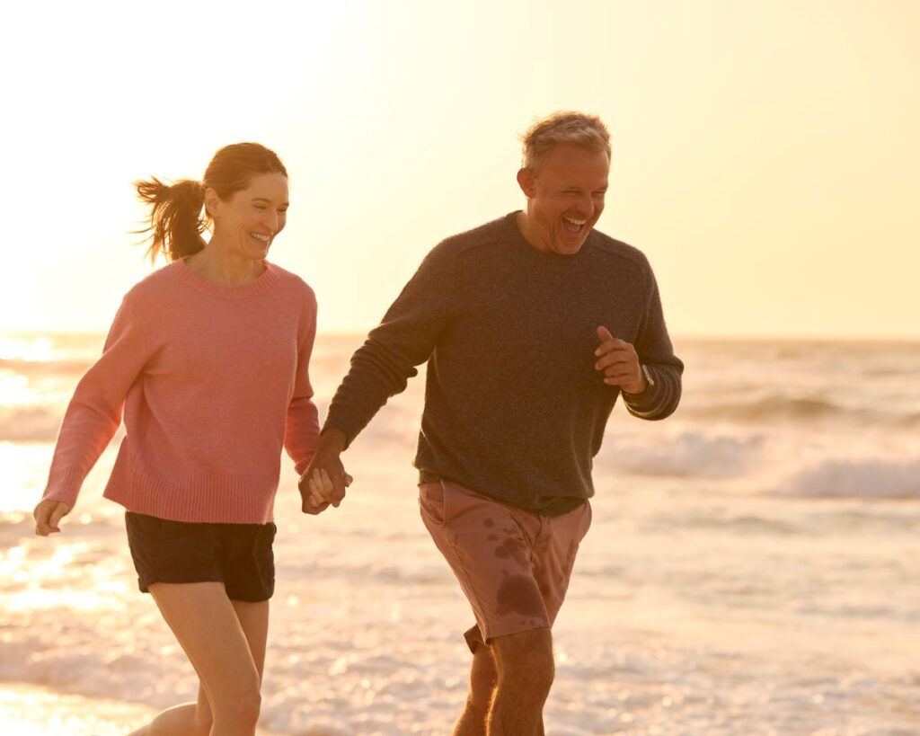 Healthy & fit retired couple walking or jogging along a beach after losing weight with Weight Loss Injections in Englewood, FL