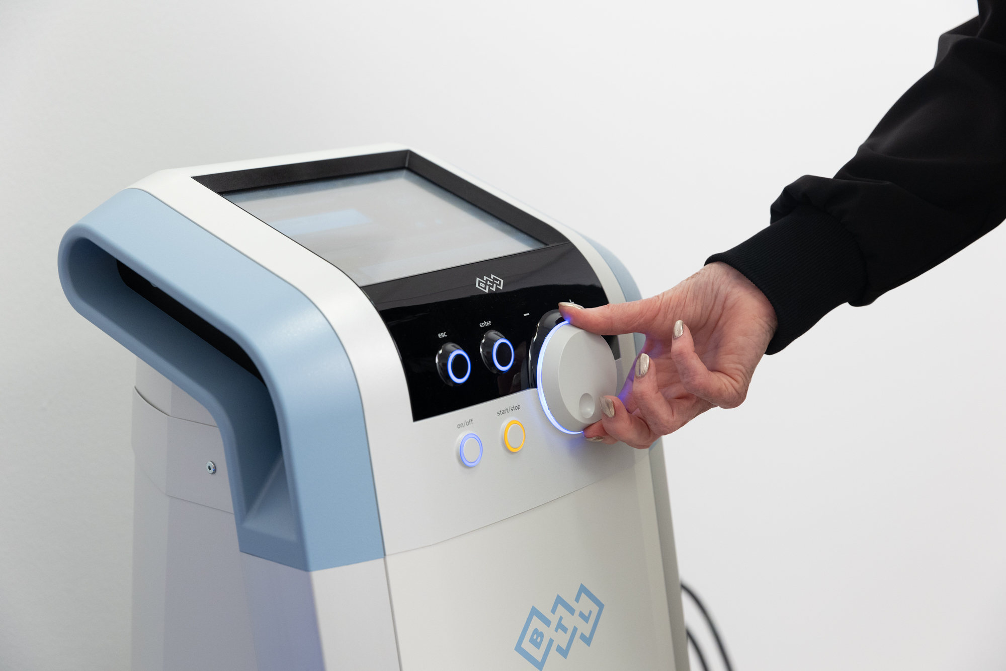 A provider adjusts the intensity of the Emsella chair by turning a dial on the workstation.