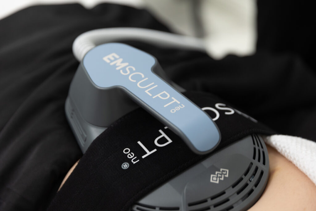 A close-up of the Emsculpt NEO paddle resting on a patient's abdomen for body contouring near Sarasota.